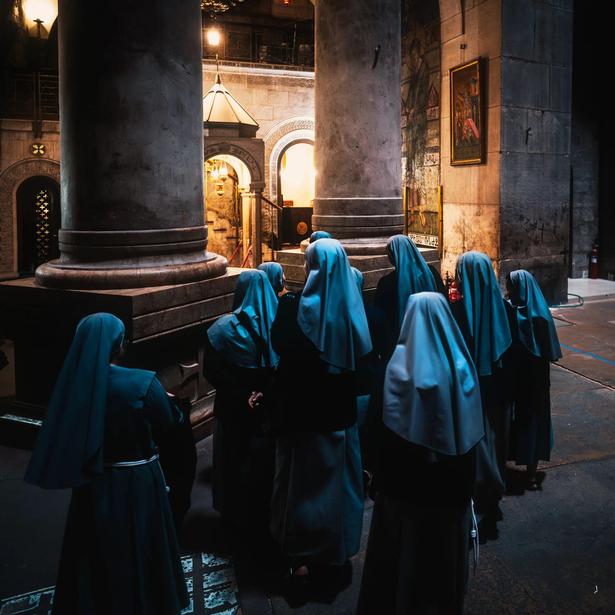 Figures in blue, walking through a colonnade